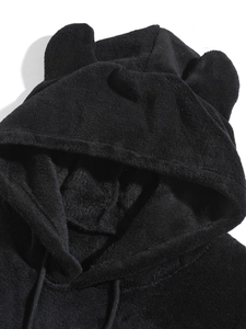 Detail of plush black hoodie featuring soft coral fleece texture and cute bear ear hood design