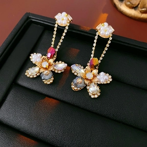 Macro shot of floral drop earrings with zircon, pearls and gold finish on black leather