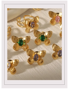 Detailed close-up of 18K gold butterfly earrings and rings with colorful gemstones
