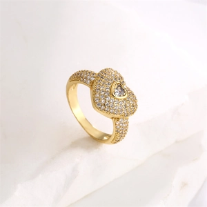 Close-up of heart-shaped gold ring with micro-paved zircons on a white textured stone