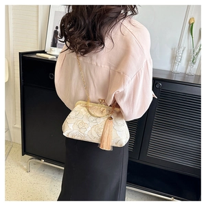 Detail of beige floral jacquard bag with metal handle and elegant tassel decoration