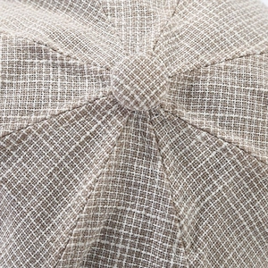 Macro detail of beige woven fabric texture and top button on retro octagonal hat
