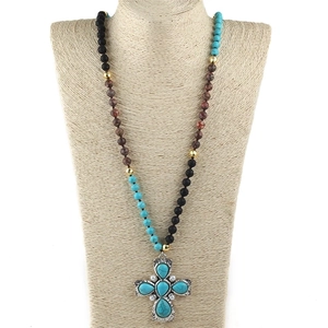 Collana lunga con perline stile bohémien e ciondolo a croce vintage su un busto per gioielli