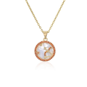 Macro shot of gold Sagittarius pendant with white shell and orange-red cubic zirconia