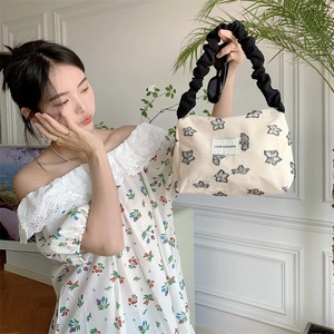 Off-white canvas tote bag with black butterfly embroidery and stylish pleated handles