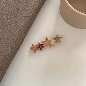 Detail shot of vintage star-shaped hair clip with multi-colored resin on gold metal