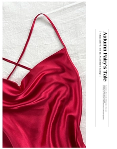 Flat lay detail of red satin sleepwear showing delicate thin straps and crisscross back design