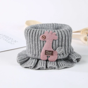 Detail of grey knitted baby neck warmer with pink giraffe decor and handmade label