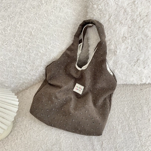 Détail du sac fourre-tout en velours côtelé marron à motifs floraux et étiquette blanche
