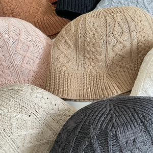 Detail view of cotton blend knit bucket hats featuring various colors and cable knit texture