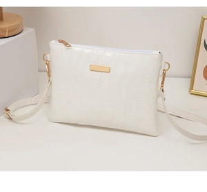 Detailed side view of a white crocodile texture PU leather crossbody bag with gold hardware