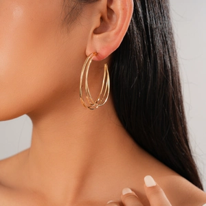 Detail shot of a triple-layered gold geometric C-shaped earring on a model
