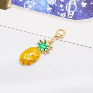 Detailed macro view of a golden pineapple charm with yellow enamel and lobster clasp