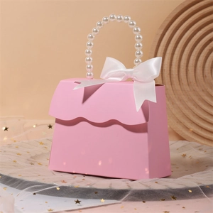 Pink wedding favor box with pearl handle and white ribbon bow on elegant tulle background