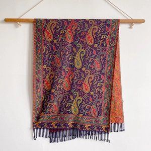 Detail view of ethnic paisley pattern cashmere-like scarf with fringe on white background