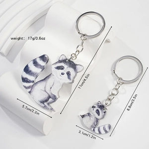 Detail view of two acrylic raccoon keychains showing sizes and weight measurements