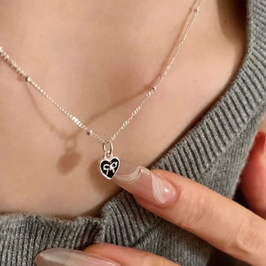 S925 silver beaded chain necklace with black heart pendant and bow detail on a model