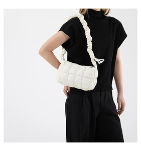 Close-up of white quilted puffer bag with ruffled strap and soft cloud texture fabric