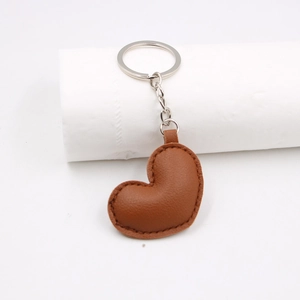 Minimalist brown heart-shaped PU leather keychain with stitched edges on white background