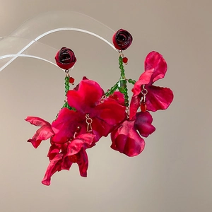 Detail view of large red fabric flower earrings with bohemian beaded tassel accents