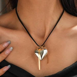 Detail of silver heart pendant with gold ribbon bow on a slim black cord necklace