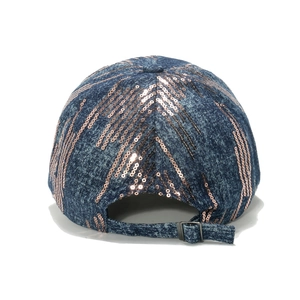 Detail of adjustable metal buckle and rose gold sequins on dark blue denim baseball cap