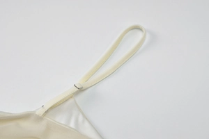 Detail view of adjustable strap with metal slider on beige cutout dress