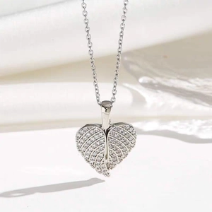 Elegant silver heart necklace with pavé zircon feathers on a white fabric background