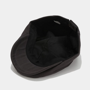 Detail view of adjustable metal buckle and breathable lining on dark gray canvas beret