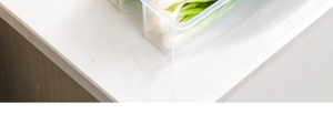 Detailed view of a transparent plastic kitchen organizer box storing fresh scallions