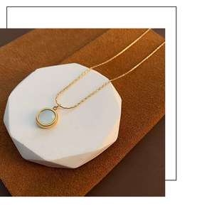 Close-up of a white mother-of-pearl pendant on a gold 18K titanium steel chain