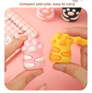 Close-up of pink and yellow silicone cat paw pencil accessories on a colorful notebook