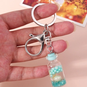 Detail of wish bottle keychain with blue glitter liquid and pearl inside close-up view