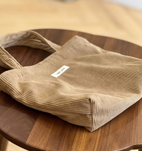 Detail of camel corduroy tote bag showing the textured fabric and simple wish logo