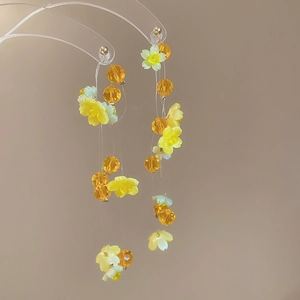 Macro shot of long floral tassel earrings with yellow and green resin flower beads