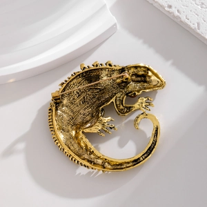 Vintage gold chameleon brooch with detailed lizard texture on a white background