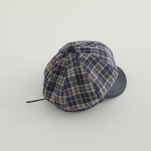 Detail view of plaid newsboy hat with dark blue fabric and black leather brim