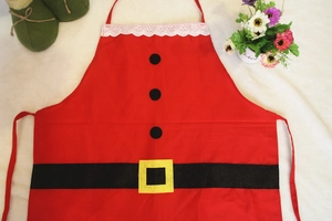 Flat lay of a red Santa Claus apron with black buttons and lace on a white plush surface