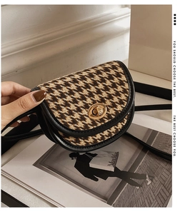 Nahaufnahme einer Mini-Satteltasche mit Hahnentrittmuster, schwarzem Leder und Drehverschluss