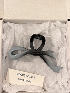 Top view of a grey gradient acrylic bow hair claw clip placed in a white gift box