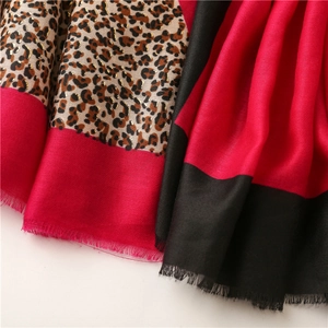 Close-up of leopard print scarf with gold shimmer, red color block and fringe edges