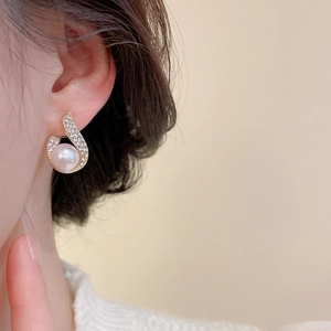 Close-up of elegant gold stud earring with opal and pearl on female model