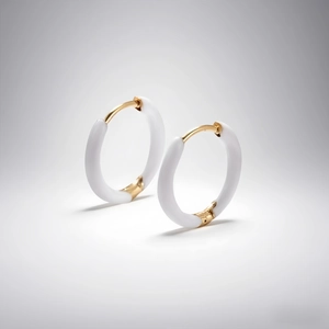 Close-up of gold and white enamel hoop earrings with secure snap-on closure detail