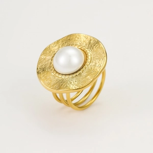 Detailed macro view of a gold textured circular ring with an inlaid white pearl center