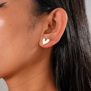 Close-up of elegant gold heart earring with white enamel inlay worn by a model