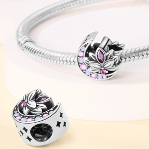 Detail of silver crescent moon and lotus charm with pink stones on a bracelet