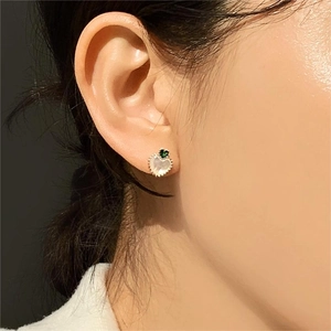 Detailed close-up of heart-shaped 925 silver earring with green zircon and white shell