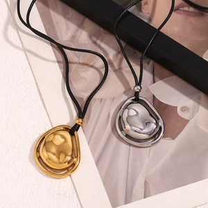 Pendenti artistici a goccia fluida in finitura oro e argento su sfondo bianco materico