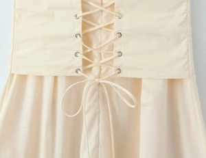 Close-up of adjustable lace-up back with metal eyelets on a cream bodycon dress