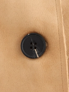 Detail of a black four-hole button on camel faux suede fabric with fine texture